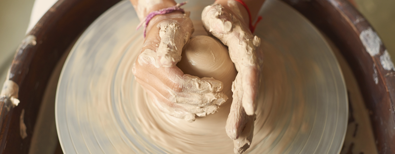 A midlife woman’s hands shaping clay on a pottery wheel, representing creative healing, beginner mindset, and the practice of presence over perfection.