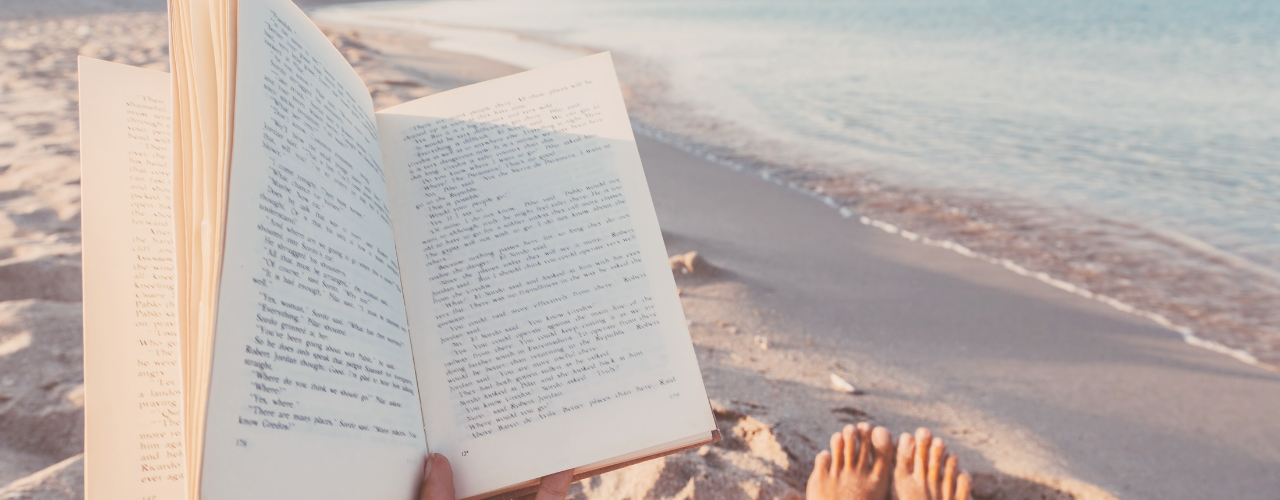 Woman reading a book on the beach, redefining rest through simple self-care and solo time for moms.